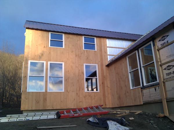 The first siding boards are up.  It's slow going because of the need to custom cut boards to fit around windows.  We stained the boards on both sides before nailing them up.