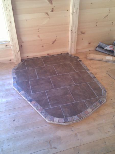 We decided to make our own wood stove hearth pad instead of buying one for $600.  We had to learn about laying tile (with the help of a book) but it came out looking good, and has an unusual, organic shape.