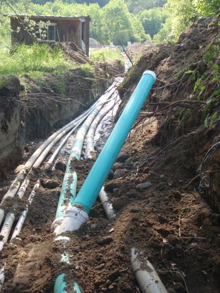 Utility trench showing all the pipes that have to run 300 feet from the old house and septic tank up to the new house. There's septic drain pipe (the green stuff with the cleanout pipe), electrical (the big grey pipe), and smaller gray pipes for phone (and future cable or fiber, not yet available here).