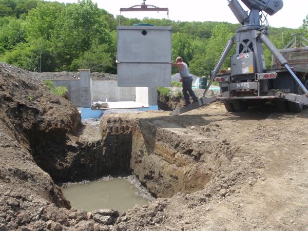 The new septic tank being lowered into place. We're running the outlet of this new tank downhill 300 feet to the old septic tank.