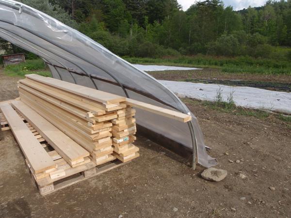 Greenhouse with end walls removed, used as a workshop for building and stacking floor beams.