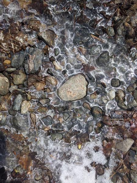 Pebbles in frozen water on trail