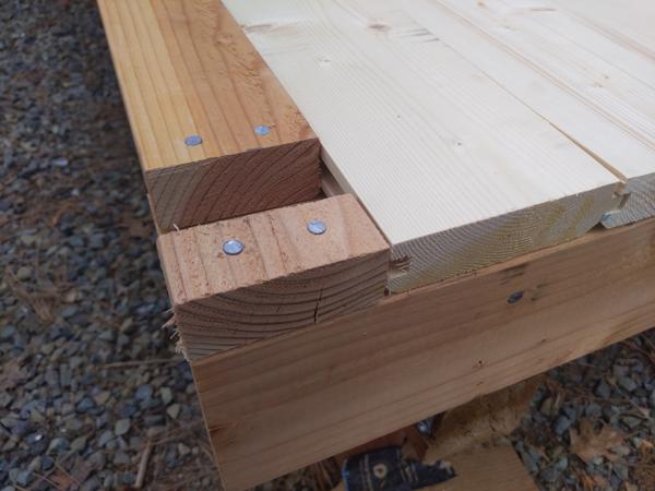 2x4s are used between the posts instead of T&G floor boards.  The tenon (middle 2x4) of the post will fit into the slot., and the two outer 2x4s of the post will cover the nails. Eventually the 2x4s and the floor boards will be sanded and finished, so the contrasting color won't be so obvious.