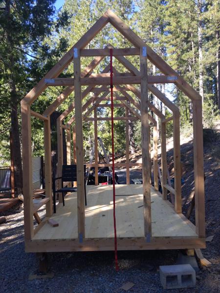 End walls are done.  The far (north) wall has an opening for a 36x54 window; the near (south) wall has an opening for a 30x80 door.  The ratchet strap kept the wall unit from flopping over while I lifted it into place.