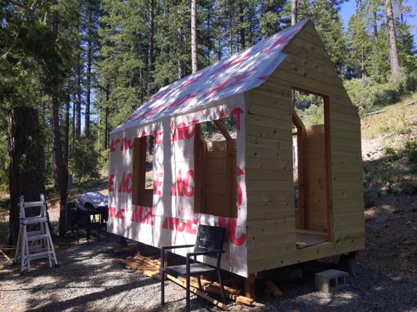House wrap is tacked to the sheathing using a hammer stapler.