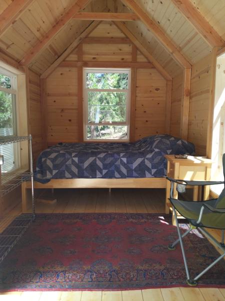 The interior is usable now.  I added a bed, a bedside table, shelves, a camp chair, and a tiny built-in laptop desk (not shown).